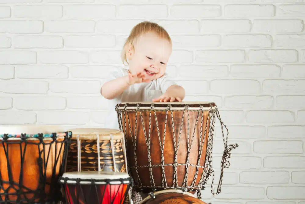 Bebê tocando tambor em momento de exploração sonora – música para bebês